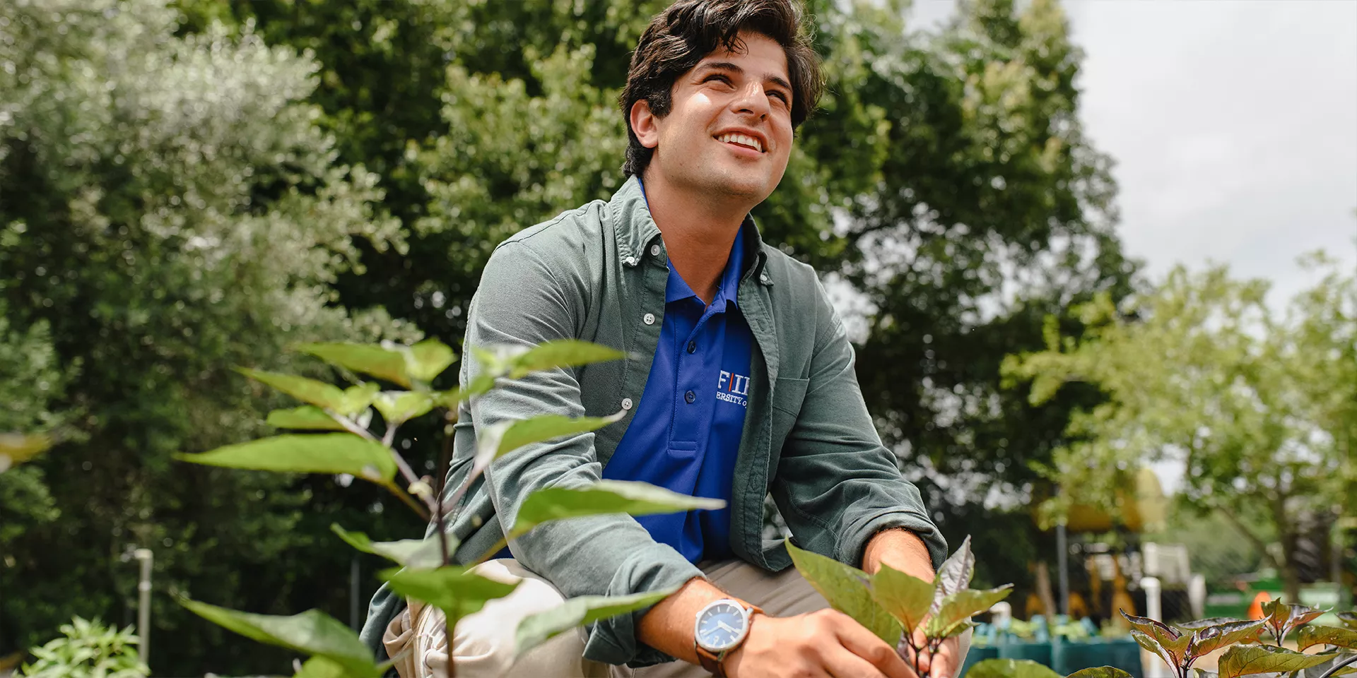 student holding plant and smiling