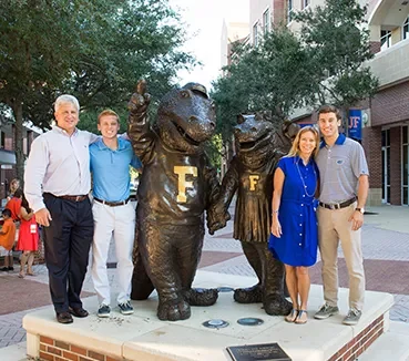 alumni standing with gator statue