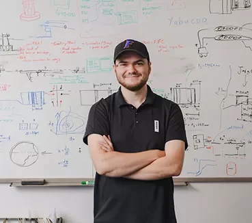 student standing in front of calculations on whiteboard