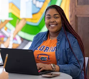 cards-programs-student-laptop Student smiling while typing on laptop