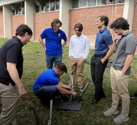 A group of UF engineers working together setting up a pole base that will be placed under a tire.