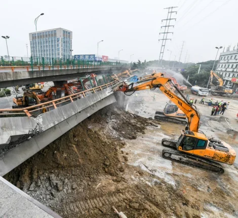 Construction vehicles next to fallen bridge