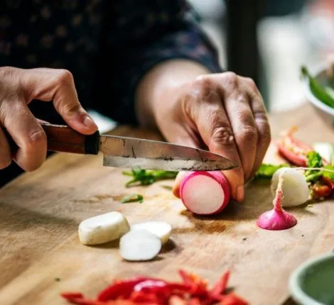 A person chops vegetables on a cutting board.
