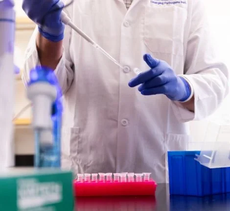 Scientist injecting something into a test tube.