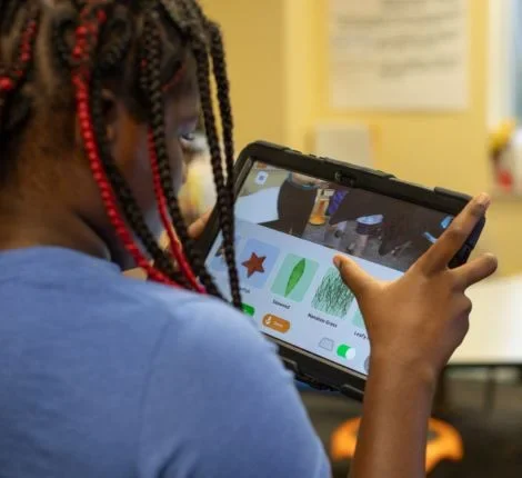 A young student is looking at a program on their tablet.
