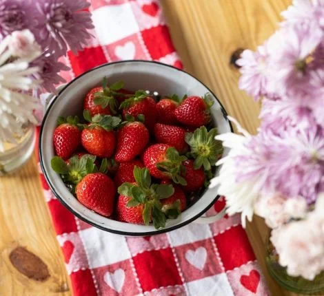 A bowl of ripe strawberries on a table.