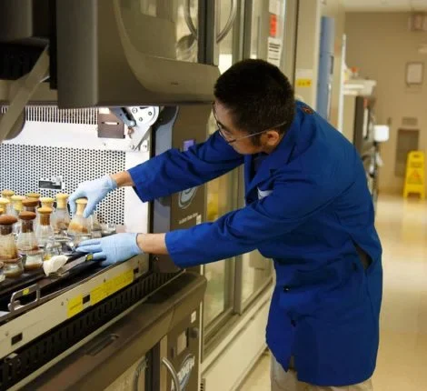 A researcher reaches into a vial.