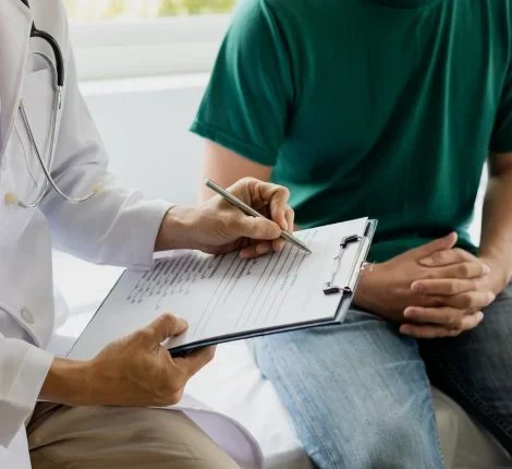A doctor sits with a patient and a clipboard
