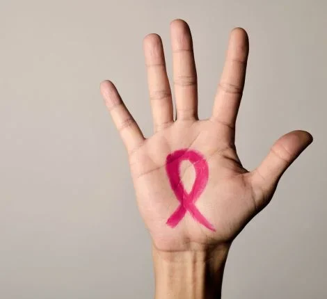 A hand with a pink ribbon for breast cancer awareness.