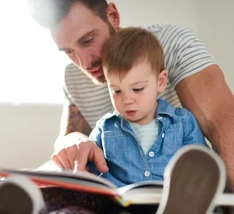 A man reads to a toddler child.
