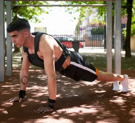 A man works out in a park with a weighted vest.