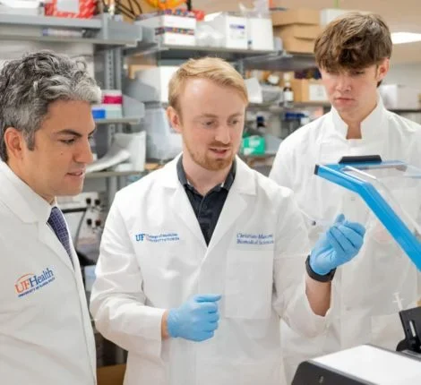 study finds covide vaccine sparks immune response Three male scientists in white coats working together in a lab.