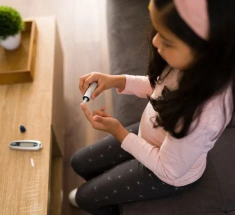 A young girl gives herself a prick to check her glucose levels
