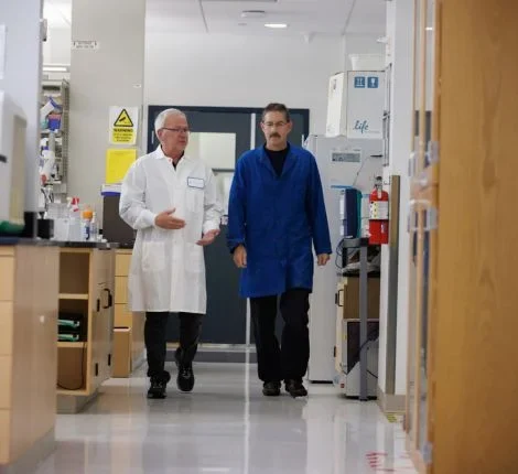 Two researchers walk together in a UF lab.