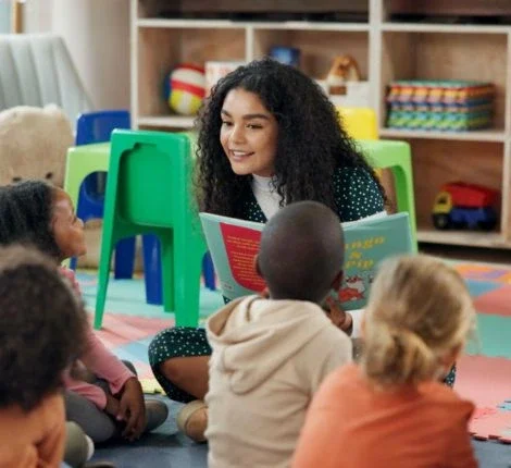 a woman sits teaching a group of children